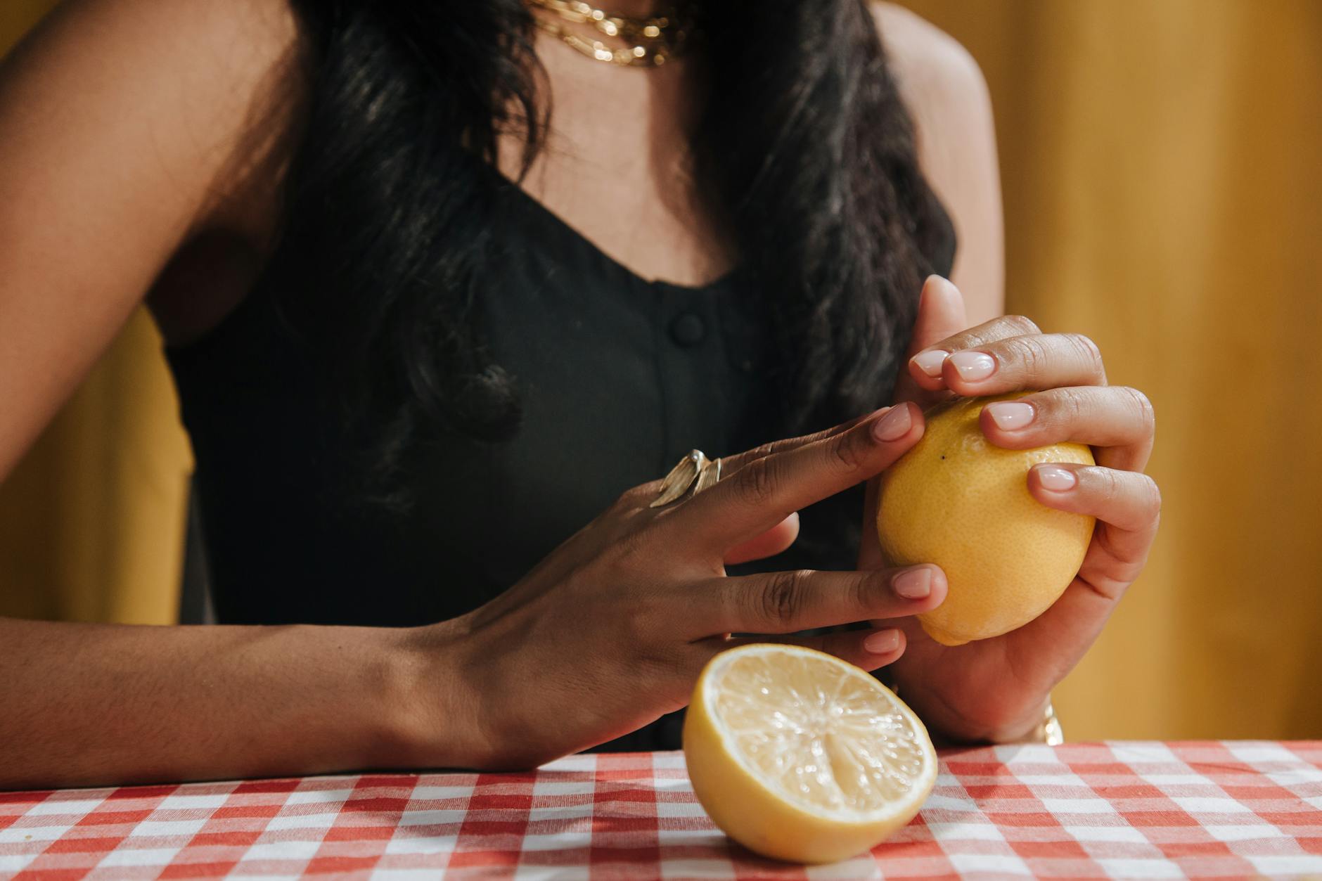 A person holding a fresh lemon at a dining table, representing the vibrant energy of new connection