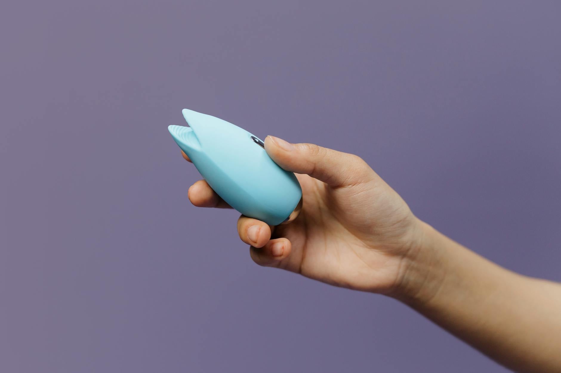 A woman holding a pink vibrator with books in the background, symbolizing intimate reconnection and trust